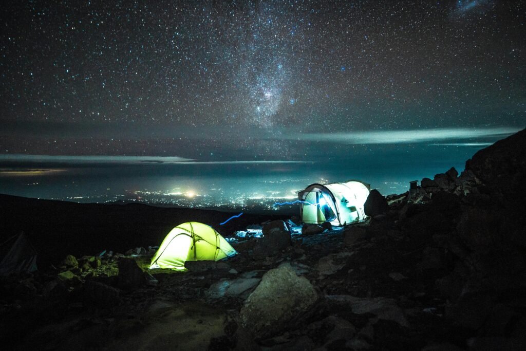 Illuminated tents on Kilimanjaro under a stunning starry sky, capturing the essence of nighttime adventure.